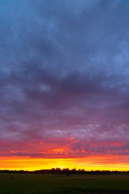 Renkli gündoğumu gökyüzüne sahip güzel bir minimalist manzara. Letonya kırsalının parlak yaz manzarası, Kuzey Avrupa.