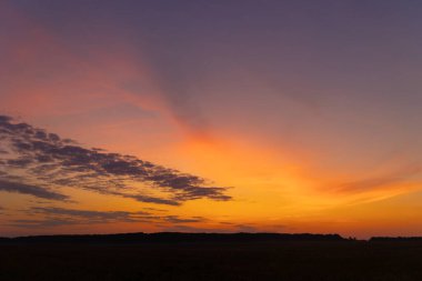 Renkli gündoğumu gökyüzüne sahip güzel bir minimalist manzara. Letonya kırsalının parlak yaz manzarası, Kuzey Avrupa.