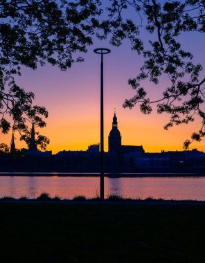 Riga, Letonya 'nın yaz gündoğumunda güzel bir şehir merkezi panoraması. Parlak gökyüzüne karşı siluetler inşa eden renkli bir manzara.