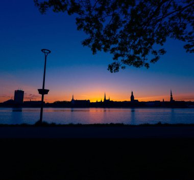 Riga, Letonya 'nın yaz gündoğumunda güzel bir şehir merkezi panoraması. Parlak gökyüzüne karşı siluetler inşa eden renkli bir manzara.