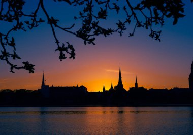 Riga, Letonya 'nın yaz gündoğumunda güzel bir şehir merkezi panoraması. Parlak gökyüzüne karşı siluetler inşa eden renkli bir manzara.