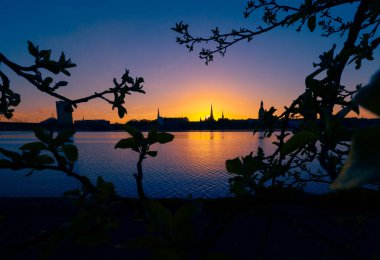 Riga, Letonya 'nın yaz gündoğumunda güzel bir şehir merkezi panoraması. Parlak gökyüzüne karşı siluetler inşa eden renkli bir manzara.