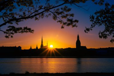 Riga, Letonya 'nın yaz gündoğumunda güzel bir şehir merkezi panoraması. Parlak gökyüzüne karşı siluetler inşa eden renkli bir manzara.