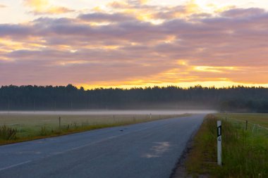 Letonya kırsalında güzel bir yaz gündoğumu. Karanlık arkaplan ile aydınlık sabah gökyüzü.