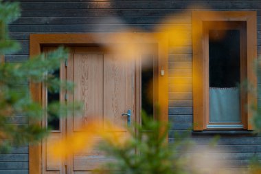 Ormanda güzel bir ahşap kulübe, sonbahar ormanlarıyla çevrili renkli yapraklarla. Dış görünüşün ayrıntıları. Letonya 'da sonbahar sezonu.