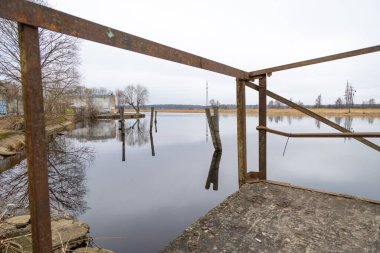 Nehir kenarında paslı demir metal yapı. Letonya Riga 'da bulutlu bir bahar günü.