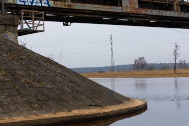 Nehir üzerindeki eski, paslı bir metal köprünün detayları. Letonya Riga 'da bahar günü bulutlu.