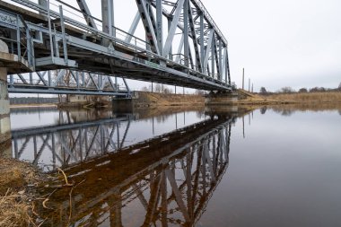 Nehir üzerinde demiryolu rayları olan iki paralel metal köprü. Riga, Letonya 'nın ilkbahar manzarası.