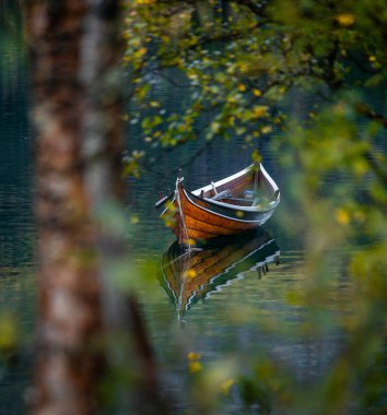 Kuzey Norveç 'teki dağlarda sonbahar gölünde yüzen güzel bir tekne. İskandinavya 'nın mevsimlik manzarası.