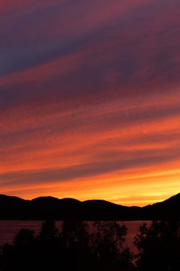 Kuzey Norveç 'te fiyort üzerinde güzel, dramatik bir günbatımı gökyüzü. İskandinavya 'nın mevsimlik manzarası.
