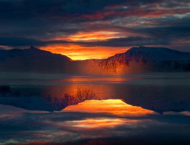 Kuzey Kutbu Norveç 'te fiyortların yukarısında gün doğumunun güzel ve sanatsal bir şekilde iki kez görülmesi. Kış mevsiminde İskandinavya 'da Kuzey Kutbu doğası.