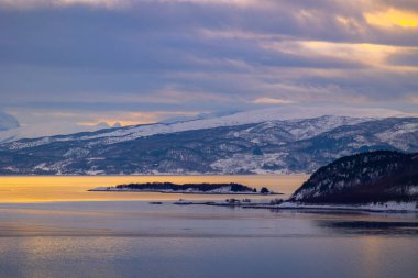 Kuzey kutup günü boyunca karlı dağlarla kaplı bir Norveç fiyordunun güzel manzarası. Kış mevsiminde İskandinavya 'da Kuzey Kutbu doğası.