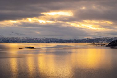 Kuzey kutup günü boyunca karlı dağlarla kaplı bir Norveç fiyordunun güzel manzarası. Kış mevsiminde İskandinavya 'da Kuzey Kutbu doğası.