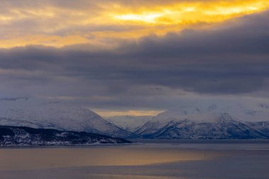 Altın saat boyunca karlı dağlarla kaplı güzel bir Norveç kış manzarası. Kış mevsiminde İskandinavya 'da Kuzey Kutbu doğası.