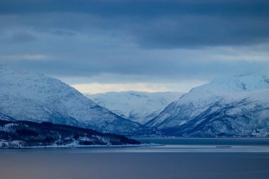Norveç fiyortlarının üzerinde kar olan güzel bir dağ manzarası. Kış mevsiminde İskandinavya 'da Kuzey Kutbu doğası.