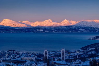 Fiyort üzerinde karlı dağları olan güzel bir kuzey şehri Narvik. Kuzey Kutbu 'ndaki bir kasabanın Norveç manzarası. Kış mevsiminde İskandinavya 'da Kuzey Kutbu doğası.