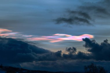 Norveç 'te kışın gökyüzünde nadir görülen bir kutup stratosferik bulut görüntüsü. Gökyüzünde güneş ışınları içinde renkli buz kristalleri. Kış mevsiminde İskandinavya 'da Kuzey Kutbu doğası.