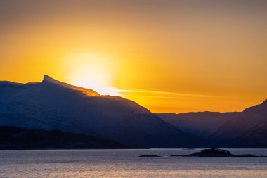 Kuzey Kutbu kışının ilk gününde karlı dağların ve fiyortların üzerinde parlayan güzel bir güneş. Kış mevsiminde İskandinavya 'da Kuzey Kutbu doğası.