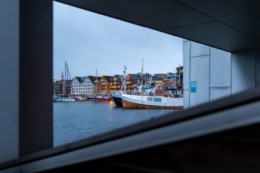Bulutlu bir kış gününde güzel bir Tromso limanı manzarası. Gemiler ve şehir binaları. Kış mevsiminde İskandinavya 'da Kuzey Kutbu doğası.