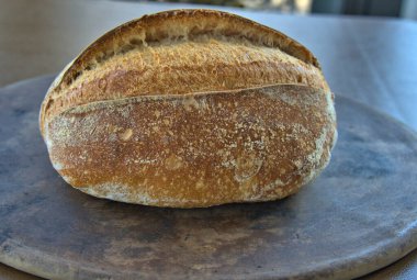 Artisan Sourdough Bread loaf on a pizza stone direct from the oven