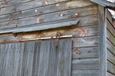Close up view of the sliding barn door hardware on a weathered old barn.