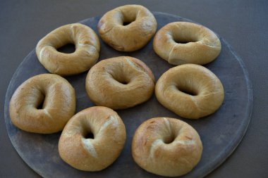 Organic Bagel on a plate with a cup of coffee in a red mug along with a newspaper and a homemade jar of organic strawberry jam and creme cheese.