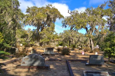 Tombstones and grave-site at Bonaventure Cemetery, Savannah, Georgia. Live Oak trees and Spanish Moss in the background.
