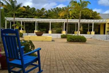 Arka planda palmiye ağaçları olan renkli bir avlusu olan tuğla bir avluda mavi sallanan sandalye..