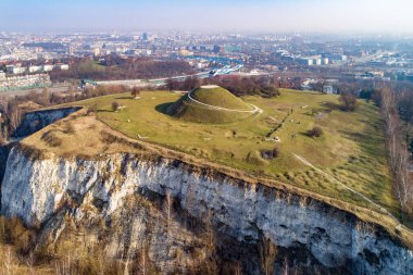 Krakus Dağı - Kopiec Krakusa Krakow 'un efsanevi kurucusunun anısına. Muhtemelen ortaçağ kurganı olan tümseğin kökeni bilinmemektedir. Öndeki eski taş ocağı. Arka planda şehir panoraması