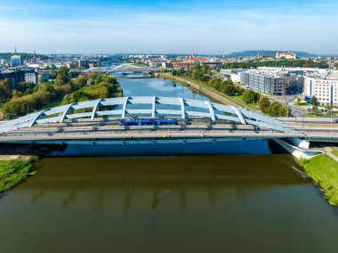 Krakow, Polonya. Şehir otoyolu, bisiklet yolu, tramvay ve Vistula nehri üzerinde mavi tramvayı olan asma köprü Kotlarski. Diğer köprüler ve arka planda Wawel şatosu olan eski kasaba. Hava görünümü