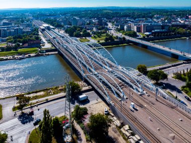 Polonya 'nın Krakow kentindeki Vistula nehri üzerinde dört raylı, yaya köprüsü ve bisiklet yolu bulunan yeni üçlü kemerli demiryolu köprüsü. Yeni Krakow Zablocie tren istasyonunun uzak görüşü. Hava görünümü