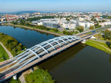 Krakow, Polonya. Dört şeritli Kotlarski köprüsü, tramvay, kırmızı bisiklet yolları ve Vistula nehri üzerinde yürüme yolları. Arka planda Wawel kalesi olan eski bir şehir. Hava görünümü