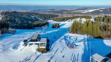 Polonya 'nın Jankulakowski Wierch Dağı' ndaki Bialka Tatrzanska kayak merkezinde kayak pisti, teleferik, kayakçılar ve snowboardcular. Gün batımında havadan 4K görüntüleme