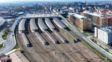 Tren Polonya 'nın Krakow kentindeki ana tren istasyonuna varmak üzere. Çatıda büyük bir park yeri, çatılı platformlar, asansörler, arabalar ve elektrikli çekiş. Arka planda ana anıtları olan eski bir kasaba. Hava yaklaşan video