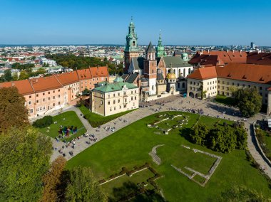 Polonya 'nın Krakow kentindeki Royal Wawel Gotik Katedrali, Rönesans Sigismund Şapeli, altın kubbe, yürüyen insanlar, ve yıkılmış eski bir bina ve iki kilisenin temelleri ile çimenlik. Hava görünümü