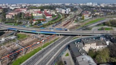 Krakow, Polonya. Çeşitli eski ve modern ulaşım araçları: tren ve tramvaylı demiryolları, otobüsler, arabalar ve şehir otoyollarının ve demiryollarının çok katlı kavşağında siyah atlı beyaz bir taksi. Havadan