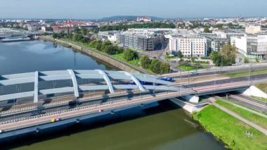 Krakow, Polonya. Vistula nehri üzerinde karayolu, tramvay, yaya köprüsü ve bisiklet yolu olan Kotlarski asma köprüsünden geçen bir tramvay. Wawel ve diğer köprülerin olduğu eski bir kasaba. Hava videosu