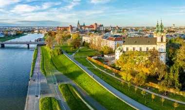 Krakow, Polonya. Gökyüzü, Skalka kilisesi ile eski sonbahar silueti Wawel kalesi ve katedrali, bir köprüsü olan Vistula nehri, ağaçlarla, yayalarla ve bisikletçilerle dolu caddeler ve geçitler.