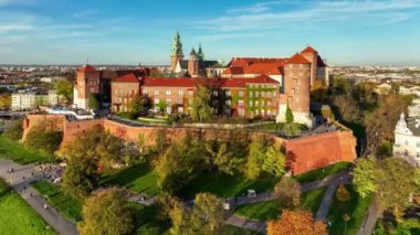 Krakow, Polonya. Wawel kraliyet kalesi ve katedrali, Vistula nehri turist botları, park, bulvarlar, yürüyen insanlar ve motorcularla gezinti. Hava 4K sonbaharda gün batımında videoyu gözler önüne seriyor