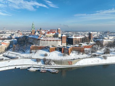 Krakow, Polonya. Kraliyet Wawel Katedrali ve kalesi kışın karla kaplı. Vistula Nehri ve turist tekneleri. Bulvarlı hava manzarası, gezinti yerleri ve yürüyen insanlar. Arka planda eski şehir