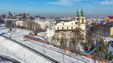 Krakow, Polonya. Skalka, St. Stanislaus Kilisesi na Skace ve Paulinite manastırı karda. Kışın havadan çekim videosu. Bulvarda yürüyen ve gezinen insanlar. Arka planda eski kasaba ve Wawel.