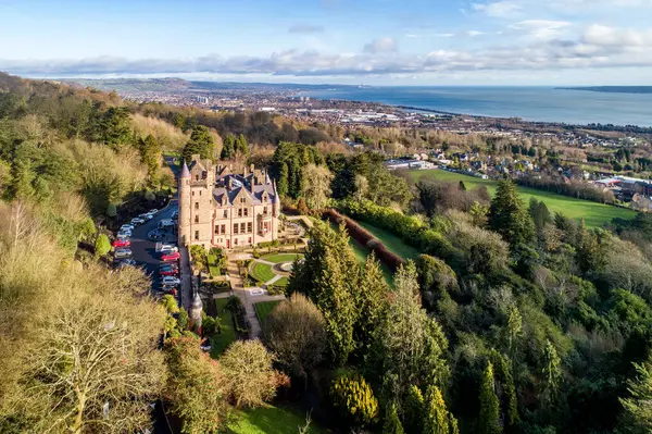 Belfast castle. Tourist attraction on the slopes of Cave Hill Country Park in Belfast, Northern Ireland. Aerial view. Belfast Lough and city in the background