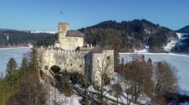 Polonya. Niedzica 'daki ortaçağ kalesi, kışın 14. yüzyıla (yukarıdaki şatoya) dayanıyor. Dunajec nehrinde donmuş yapay Czorsztyn gölü. 4K video yaklaşıyor