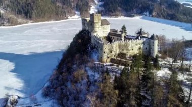 Polonya. Niedzica 'daki ortaçağ kalesi, kışın 14. yüzyıla (yukarıdaki şatoya) dayanıyor. Dunajec nehrinde donmuş yapay Czorsztyn gölü. 4K video görüntüsü