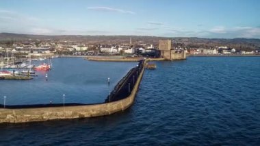 Ortaçağ Norman Kalesi ve Carrickfergus Limanı. Gün doğumunda Belfast yakınlarında. Yat limanı, tekne rampası, dalgakıran ve kasaba ile havadan 4K uçuş videosu