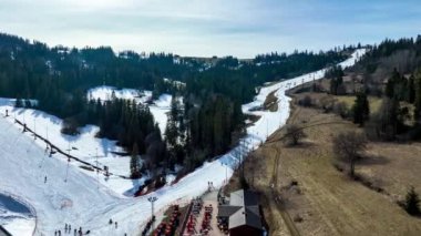 Polonya 'daki Bialka Tatrzanska kayak merkezinde kayak pistleri, teleferikler, kayakçılar ve snowboardcular. Hava 4K tarama videosuna yaklaşıyor