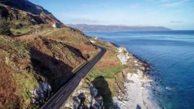 Kuzey İrlanda, İngiltere, kayalıkları olan Atlantik kıyıları. Causeway Coastal Route namı diğer Antrim Coast Road. Avrupa 'nın en manzaralı kıyı yollarından biri. Hava 4K videosu. Kış, gün doğumu