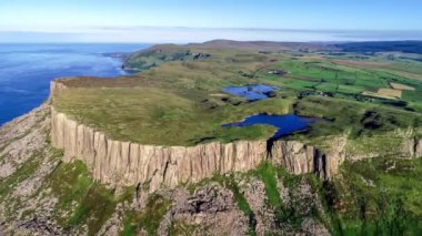 Fair Head ya da Benmore büyük uçurumu ve Ballycastle yakınlarındaki burnu. Atlantik kıyısı, Antrim İlçesi, Kuzey İrlanda, İngiltere. Atlantik Okyanusu ve gölleriyle gün batımında 4K video görüntüsü. Torr Head 'in uzak görüntüsü
