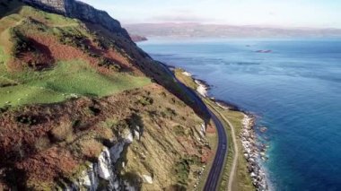 Kuzey İrlanda, İngiltere, kayalıkları olan Atlantik kıyıları. Causeway Coastal Route namı diğer Antrim Coast Road. Avrupa 'nın en manzaralı kıyı yollarından biri. Hava 4K videosu. Kış, gün doğumu