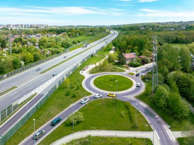 Krakow, Polonya 'da üç şeritli A4 otoyolu. Giriş rampası ve çıkış rampası, trafik çemberi, arabalar ve gürültü engelleri. Hava görünümü